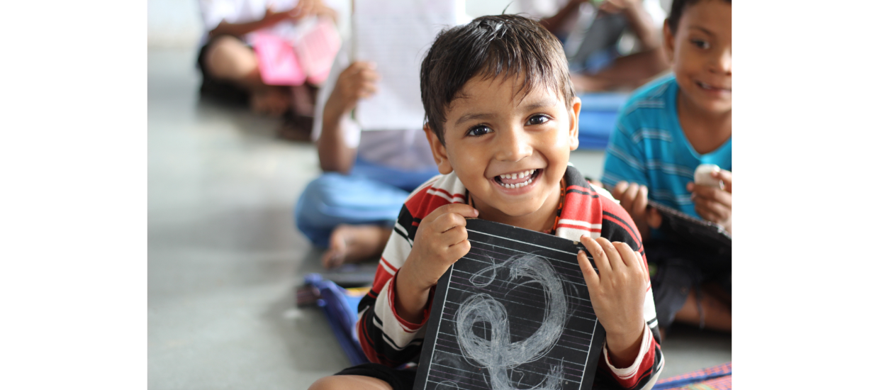 child smiling with small chalkboard