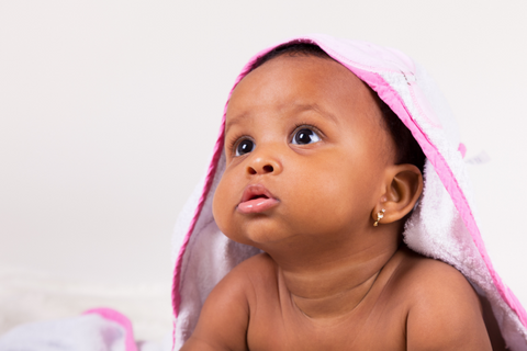 infant with blanket on head looking up